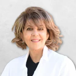 Dr. Mitra Elisha Simanian is wearing a white doctors coat over a black top