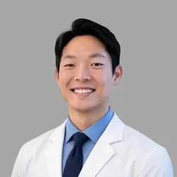 Jason in a white lab coat, blue dress shirt, and navy tie
