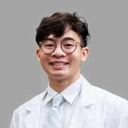 JOhnathan Tran in a white lab coat, white dress shirt, and light blue striped white tie