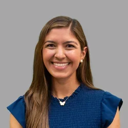 Dr. Ariana Kermani is wearing a dark blue blouse with short sleeves.