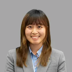 Dr. Sophie Kim is wearing a gray sport coat over a blue collared shirt.