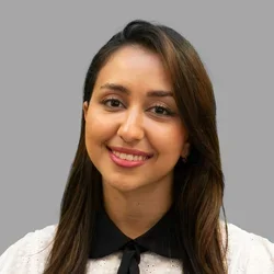Dr. Kiana Saadatmand is wearing a white short-sleeve blouse with a black collar and tie.