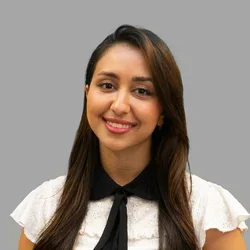 Dr. Kiana Saadatmand is wearing a white short-sleeve blouse with a black collar and tie.