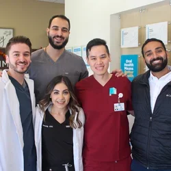Five dental practitioners posing and smiling