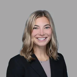 Dr. Caitlin Neapole is wearing a dark navy blazer over a soft taupe blouse.