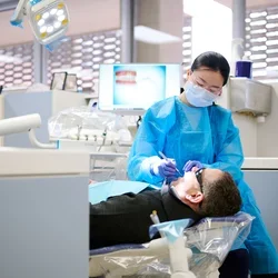 A dental resident performs a procedure on a patient.