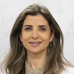 Rana Al Racheed is wearing a light brown scubs with a medical coat.