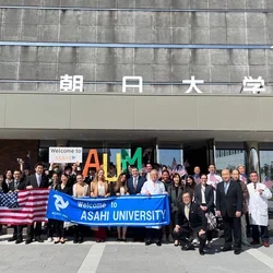 Large group in front of banners and a gray building