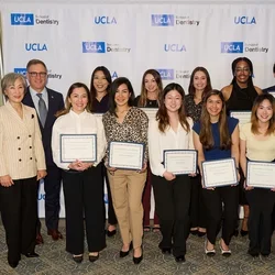 Group of 15 people smiling, many holding awards
