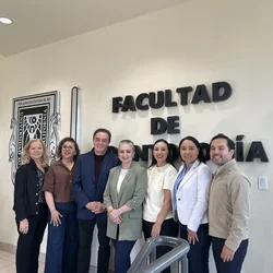 Seven people in front of sign reading "Faculdad de"