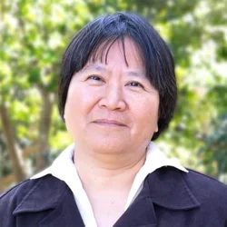 Dr. Yi-Ling Lin is wearing a blouse and a jacket in an outdoor setting.
