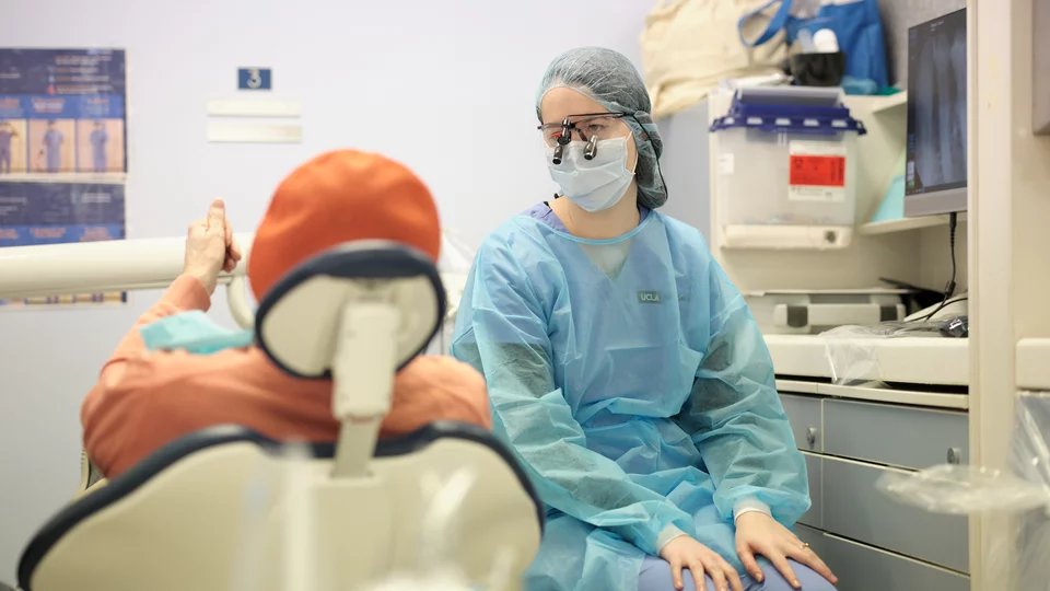 Dentist sitting next to patient in chair