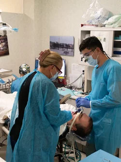 Two dentists working with a sedated patient