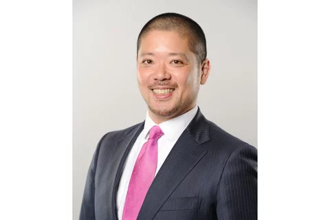 Dr. Yusuke Hamada smiling, wearing a black suit with pink tie