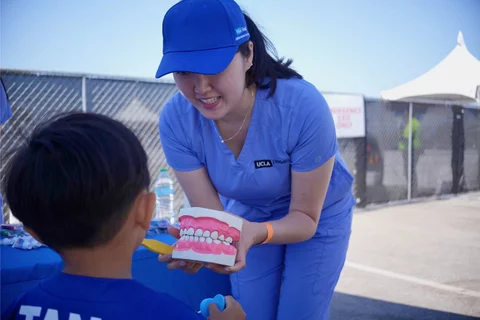 Female dental student demonstrating a mouth model to a child