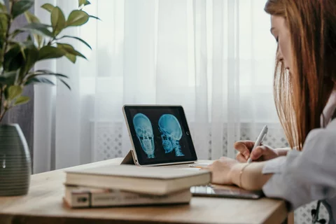 Female physician looking at skull x-ray on tablet