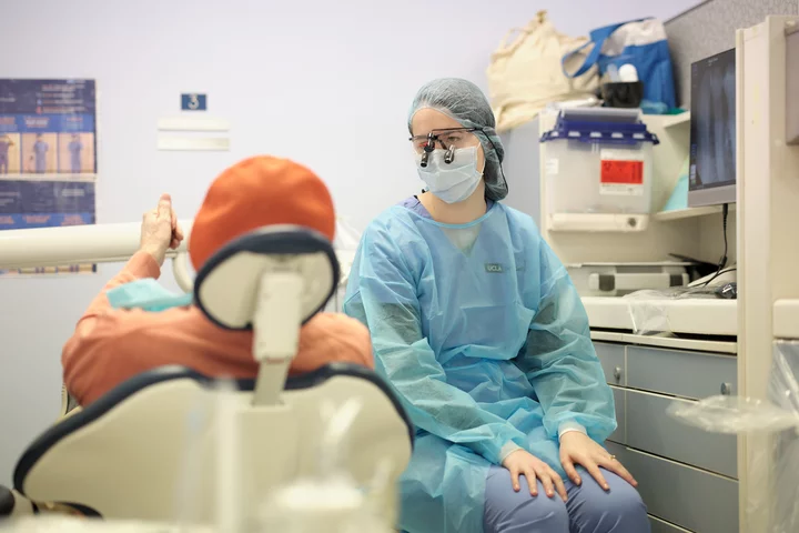 Dentist sitting next to patient in chair