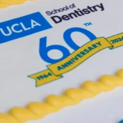 A blue, yellow, and white cake with the text "UCLA School of Dentistry 60th Anniversary 1964-2024"