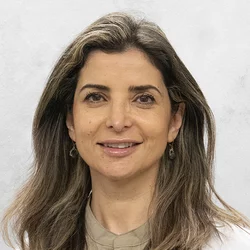 Rana Al Racheed is wearing a light brown scubs with a medical coat.