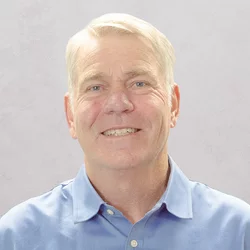 Dr. White is wearing a light blue button-up shirt with a collar.