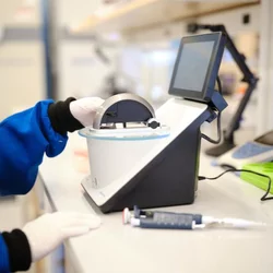 Hands using a nanodrop in a lab.